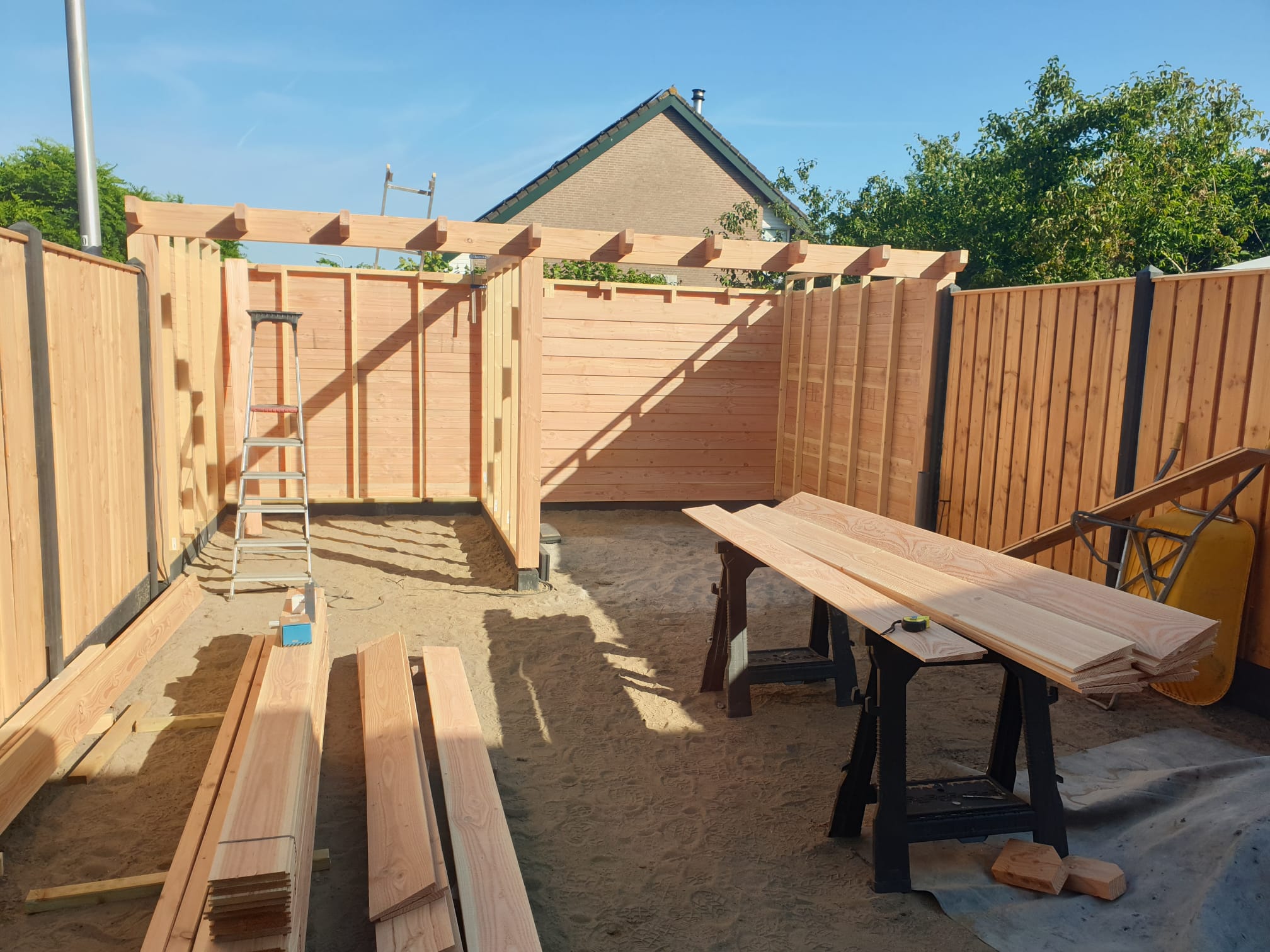 Houten frame van een tuinhuis tussen nieuwe houten schuttingen